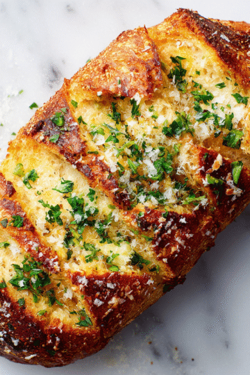 Delicious house favorite garlic bread topped with parmesan, perfect for holiday dinners