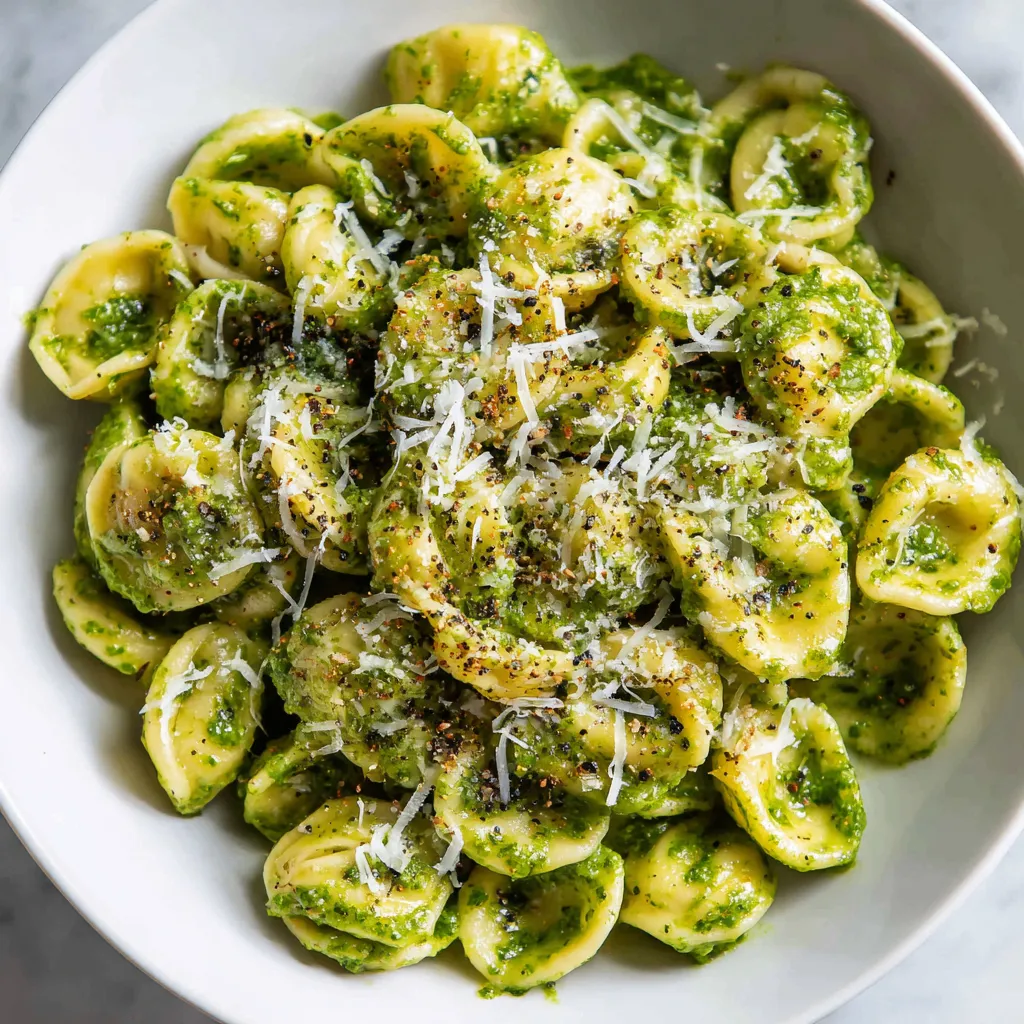A delicious pesto pasta made with fresh basil, garlic, and Parmesan cheese, garnished with extra cheese and pepper for a flavorful meal.