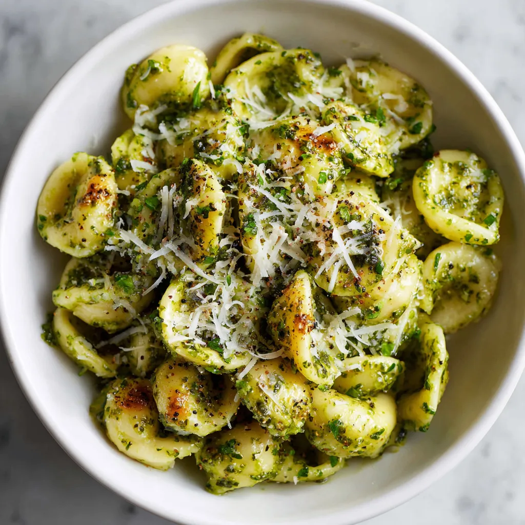 A delicious pesto pasta made with fresh basil, garlic, and Parmesan cheese, garnished with extra cheese and pepper for a flavorful meal.