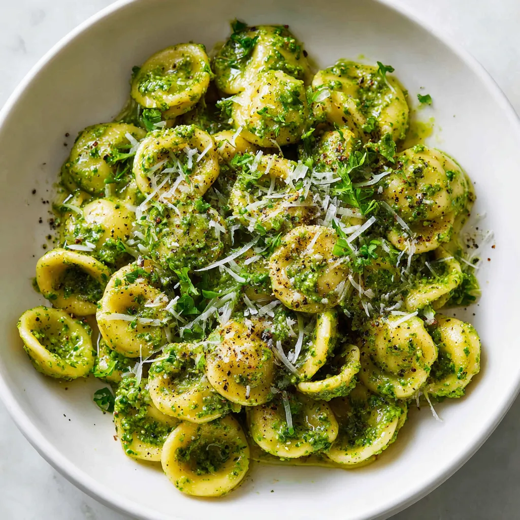 A delicious pesto pasta made with fresh basil, garlic, and Parmesan cheese, garnished with extra cheese and pepper for a flavorful meal.