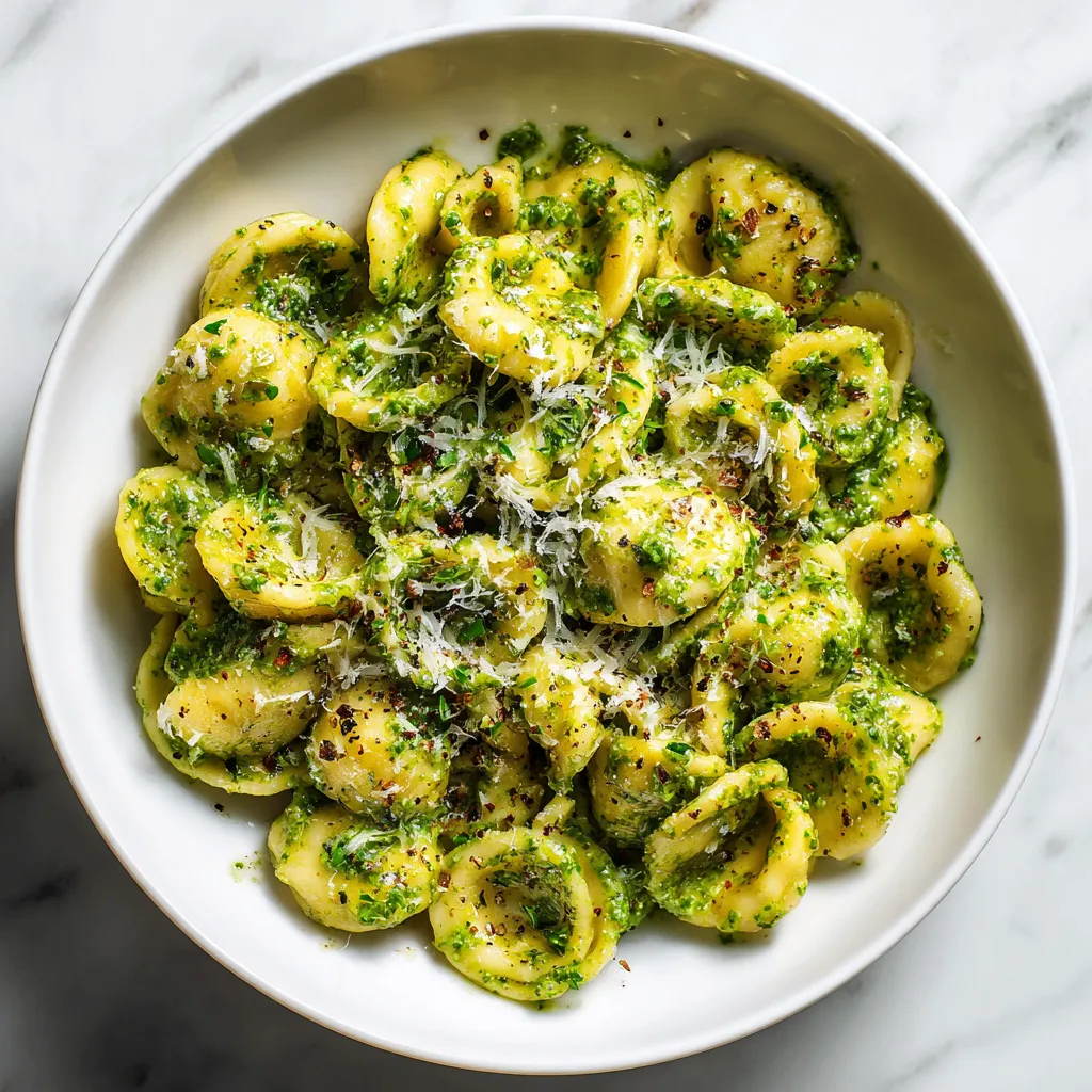 A delicious pesto pasta made with fresh basil, garlic, and Parmesan cheese, garnished with extra cheese and pepper for a flavorful meal.