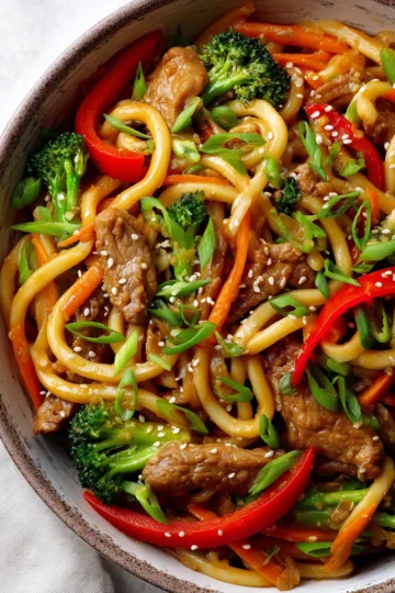 Stir-fry pork udon noodles with colorful vegetables ready to serve.