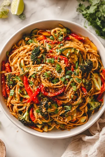 Peanut Noodles with Roasted Vegetables Bowl of peanut noodles with colorful roasted vegetables, garnished with scallions and sesame seeds, perfect for weeknight dinners and potlucks.