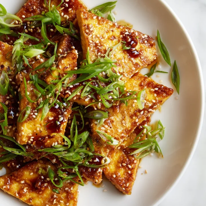 Crispy pan-fried soy tofu served with garnish, a perfect vegan dish packed with umami flavor.