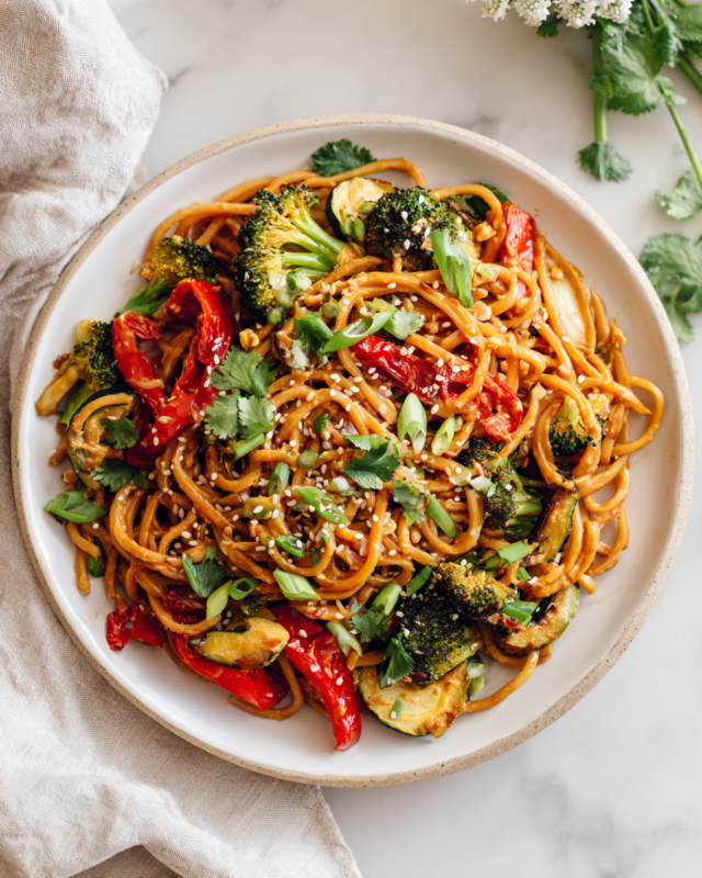 Peanut Noodles with Roasted Vegetables Bowl of peanut noodles with colorful roasted vegetables, garnished with scallions and sesame seeds, perfect for weeknight dinners and potlucks.