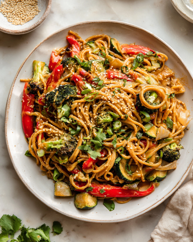 Peanut Noodles with Roasted Vegetables Bowl of peanut noodles with colorful roasted vegetables, garnished with scallions and sesame seeds, perfect for weeknight dinners and potlucks.