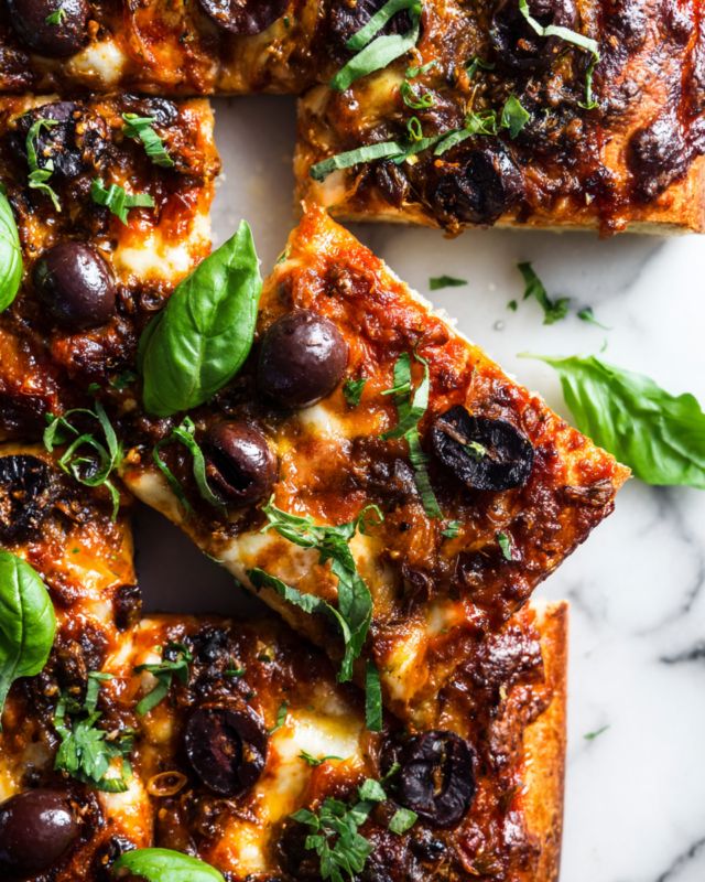 Delicious sheet pan puttanesca pizza with vibrant flavors, perfect for holiday gatherings, rich in olives and capers, topped with cheese.