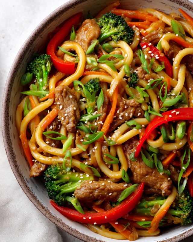 Stir-fry pork udon noodles with colorful vegetables ready to serve.