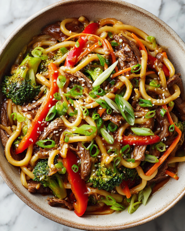 Stir-fry pork udon noodles with colorful vegetables ready to serve.